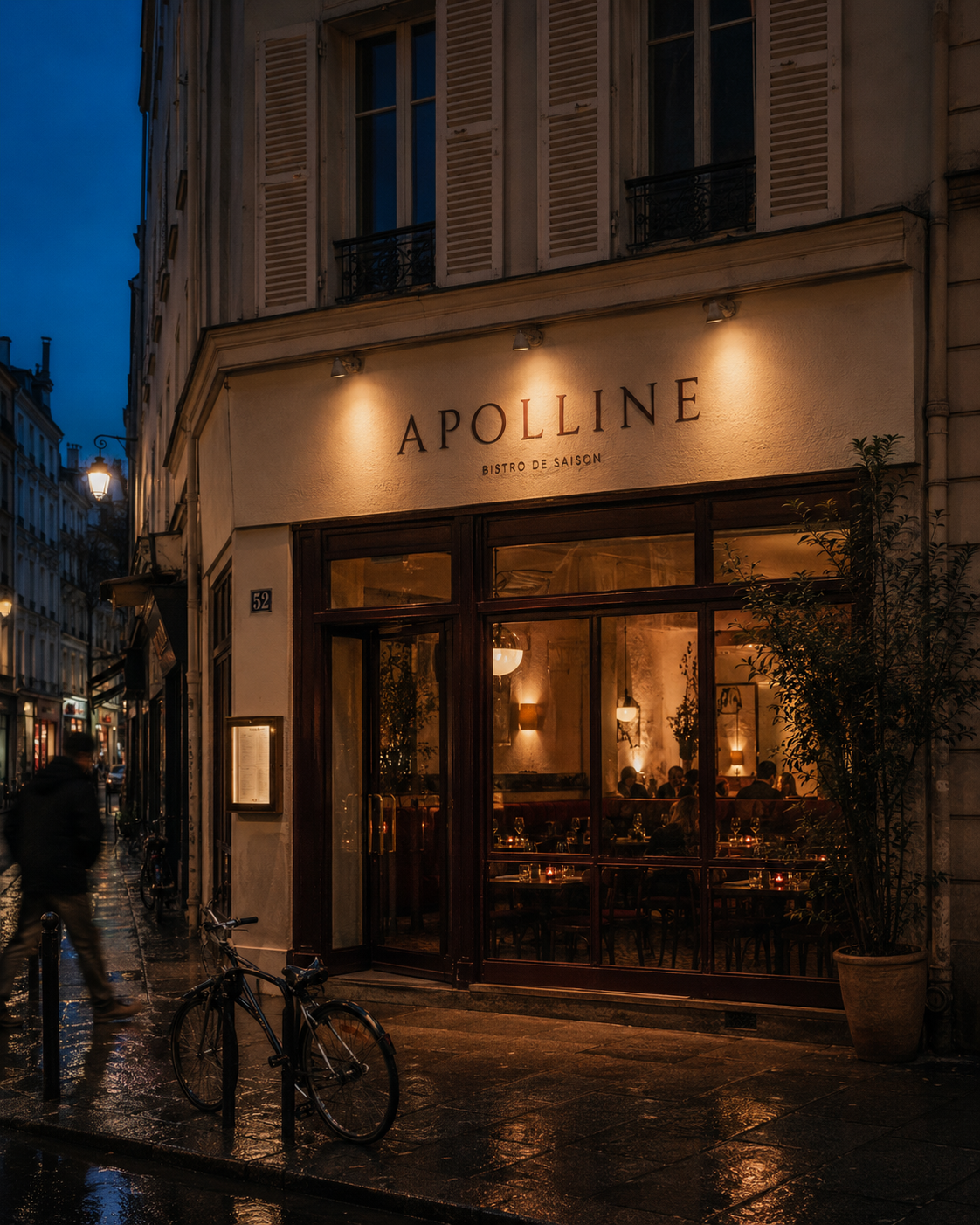 Façade d'Apolline la nuit, enseigne éclairée, vélo appuyé contre la vitrine, rue pavée humide dans le 11e arrondissement.